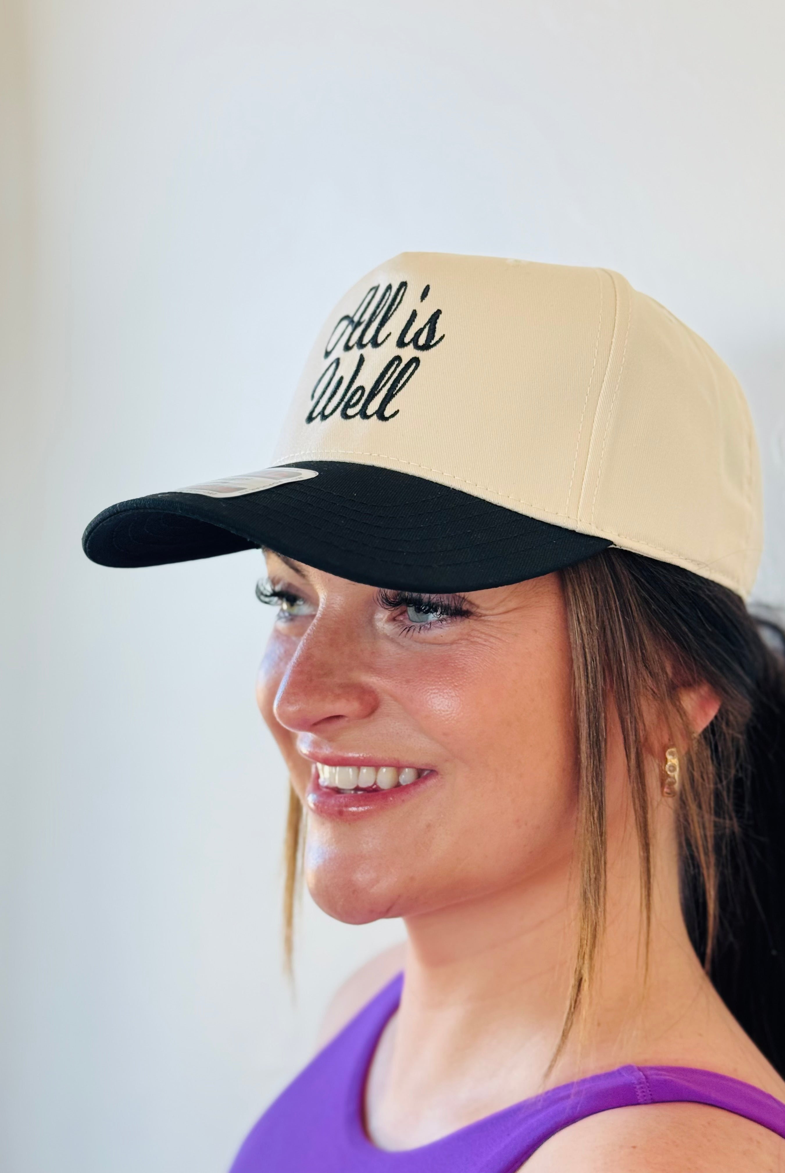 Lifestyle shot of the ALL IS WELL EMBROIDERED TRUCKER HAT being worn, demonstrating its versatility and trendy appeal.