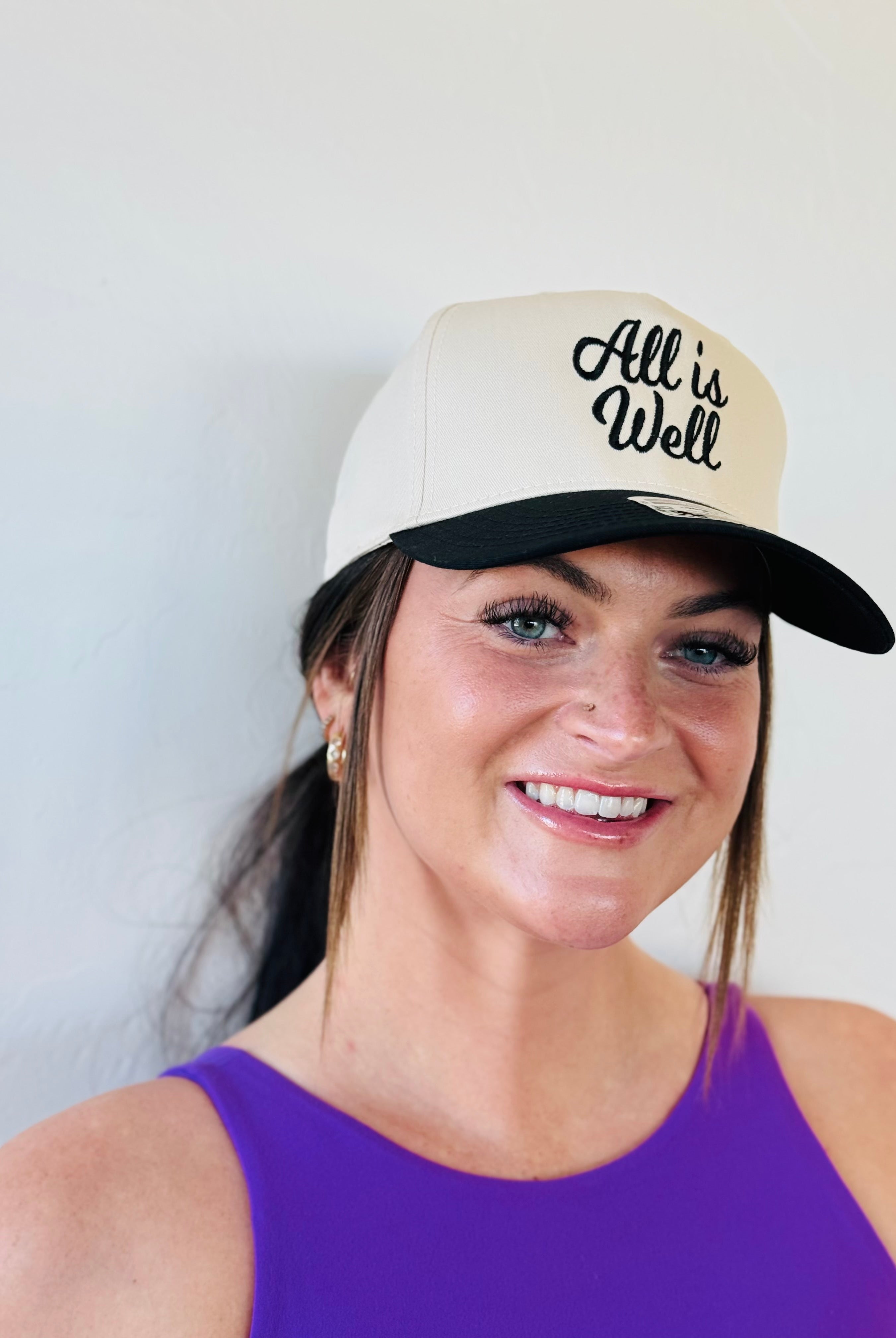 ALL IS WELL EMBROIDERED TRUCKER HAT showcasing bold black embroidery against a natural color background, perfect for outdoor style.