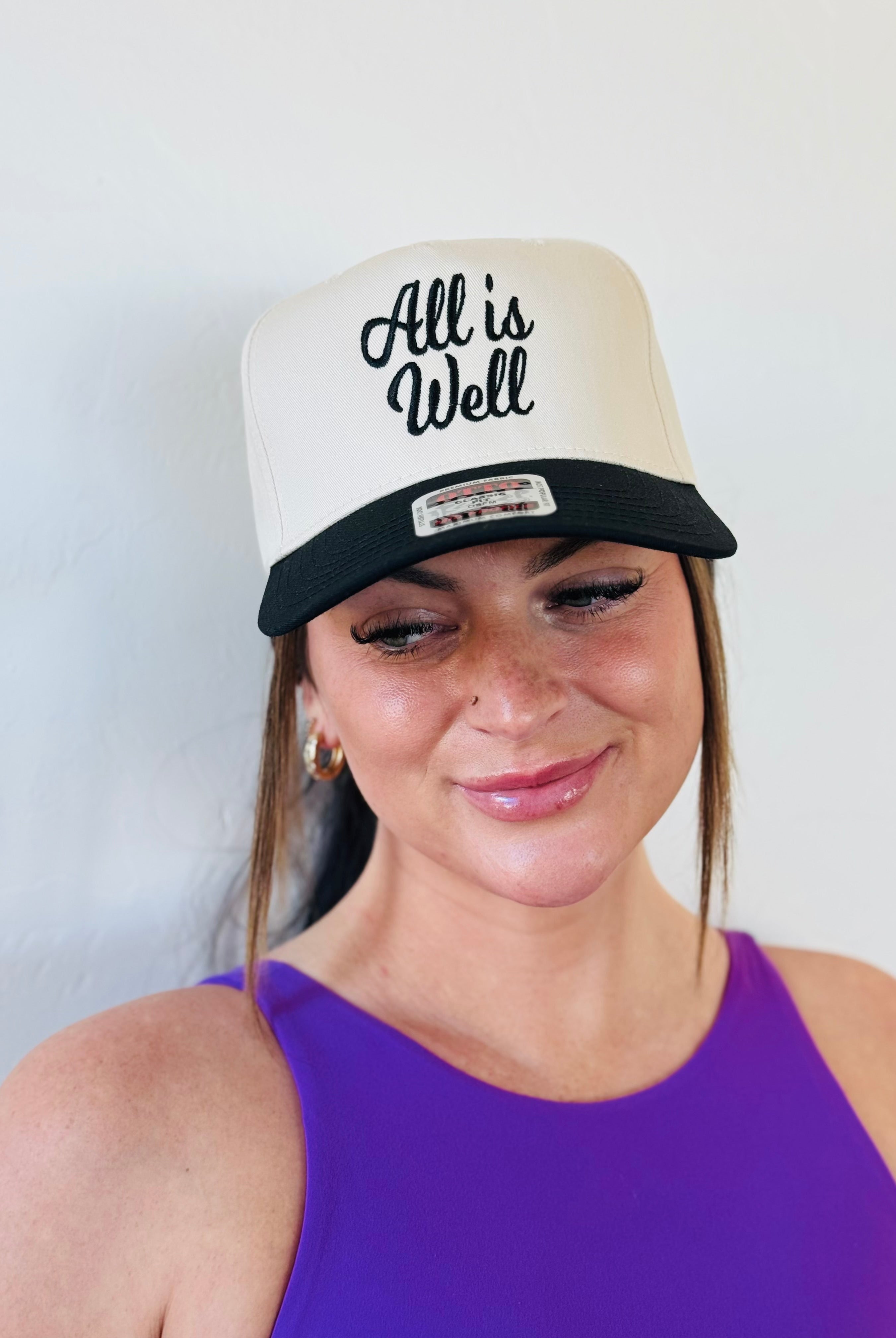 Side view of the ALL IS WELL EMBROIDERED TRUCKER HAT showcasing its detailed craftsmanship and trendy design, ideal for a versatile addition to your wardrobe.