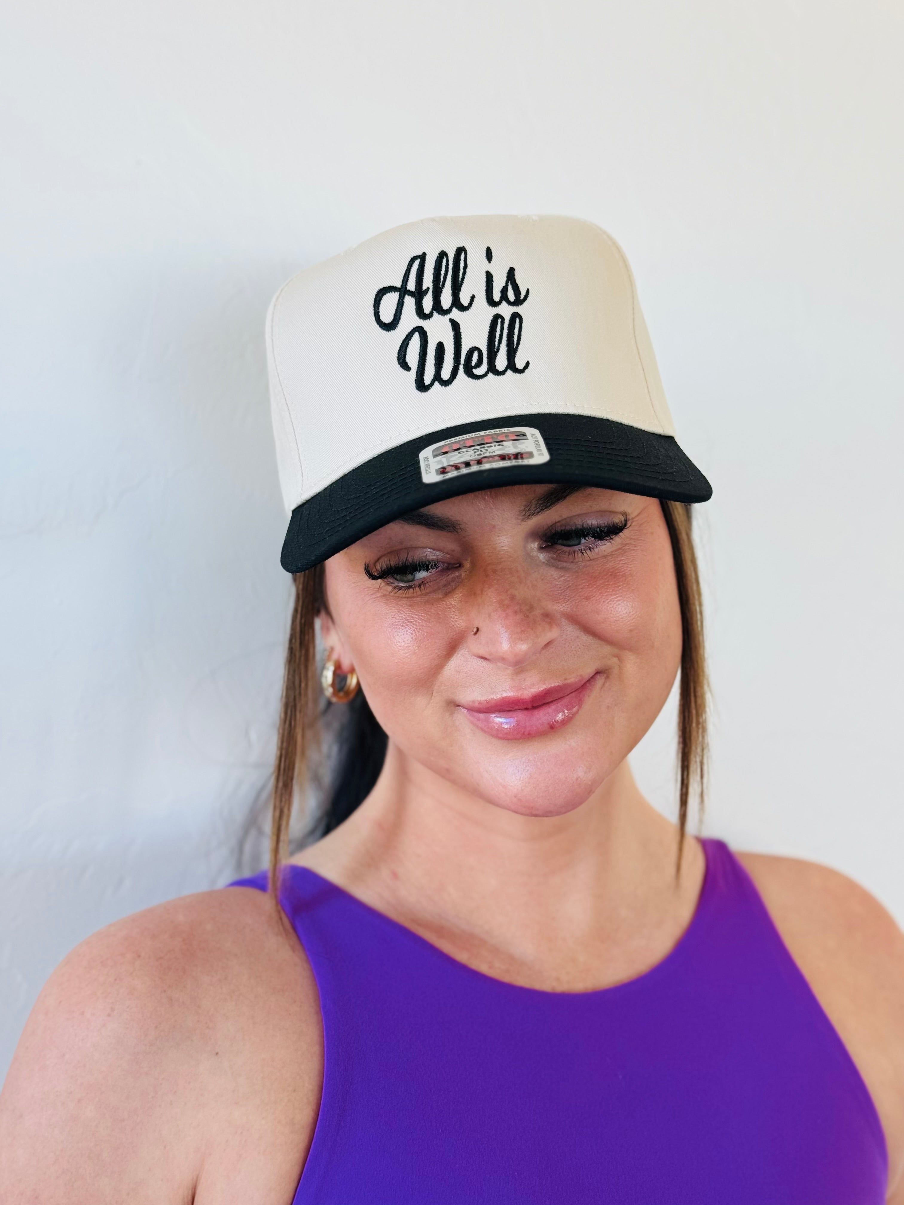 Side view of the ALL IS WELL EMBROIDERED TRUCKER HAT showcasing its detailed craftsmanship and trendy design, ideal for a versatile addition to your wardrobe.