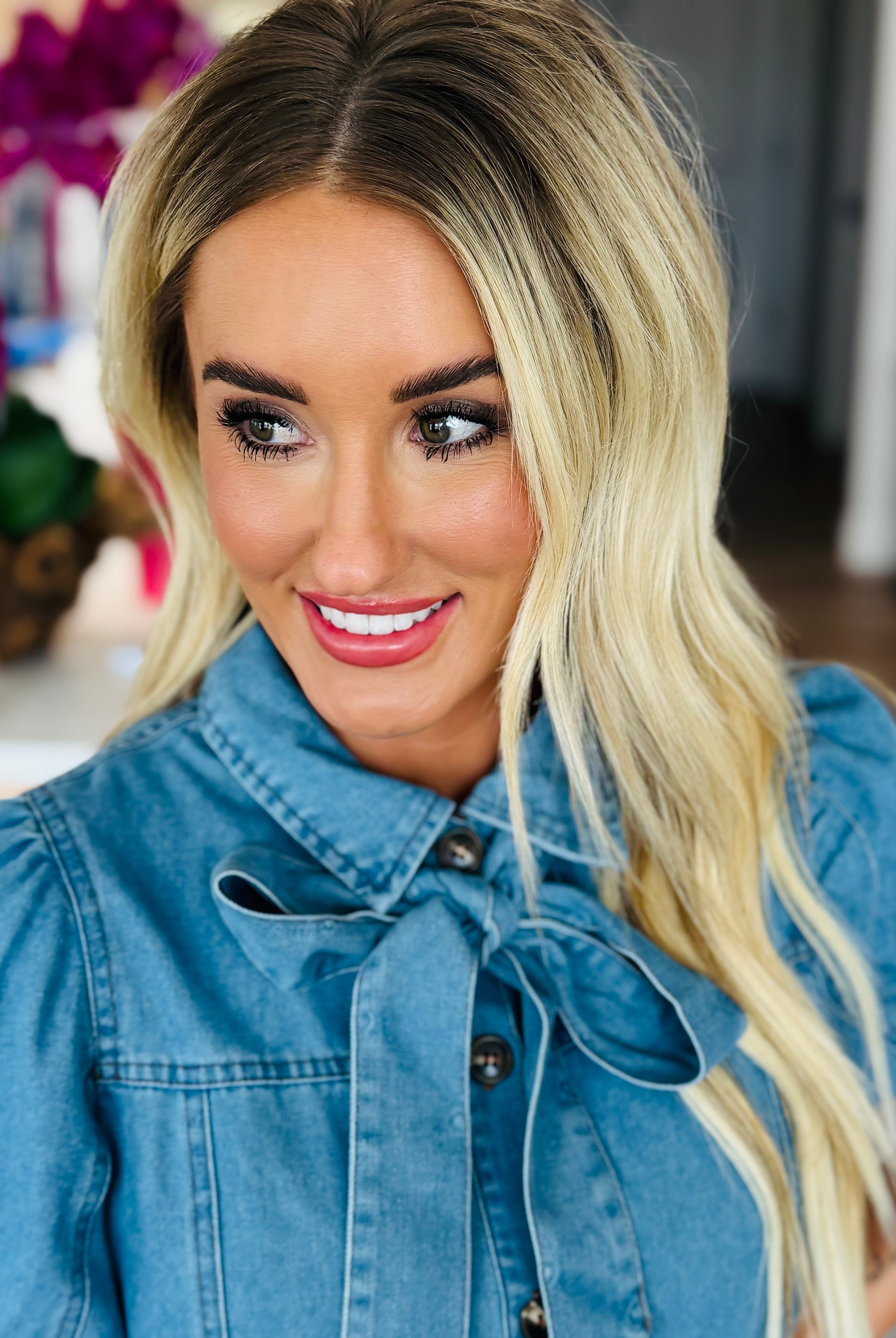 Close-up of the Entro denim dress with bow tie neck, highlighting the button-down design and playful details.