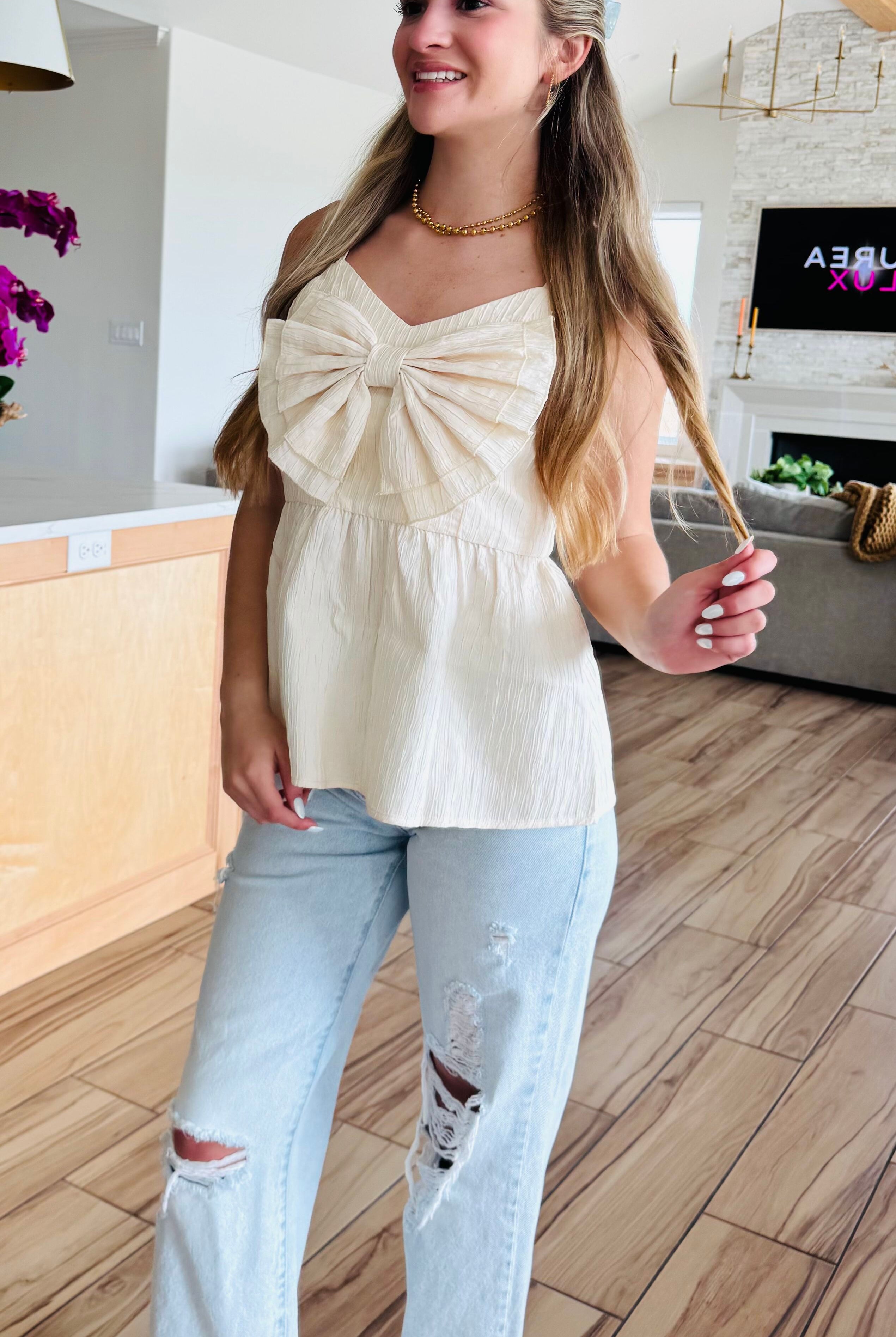 Model wearing the ECRU BABYDOLL TEXTURED BOW TOP, demonstrating its versatility when paired with jeans for a chic and effortless look.