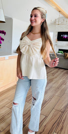 Model wearing the ECRU BABYDOLL TEXTURED BOW TOP, demonstrating its versatility when paired with jeans for a chic and effortless look.