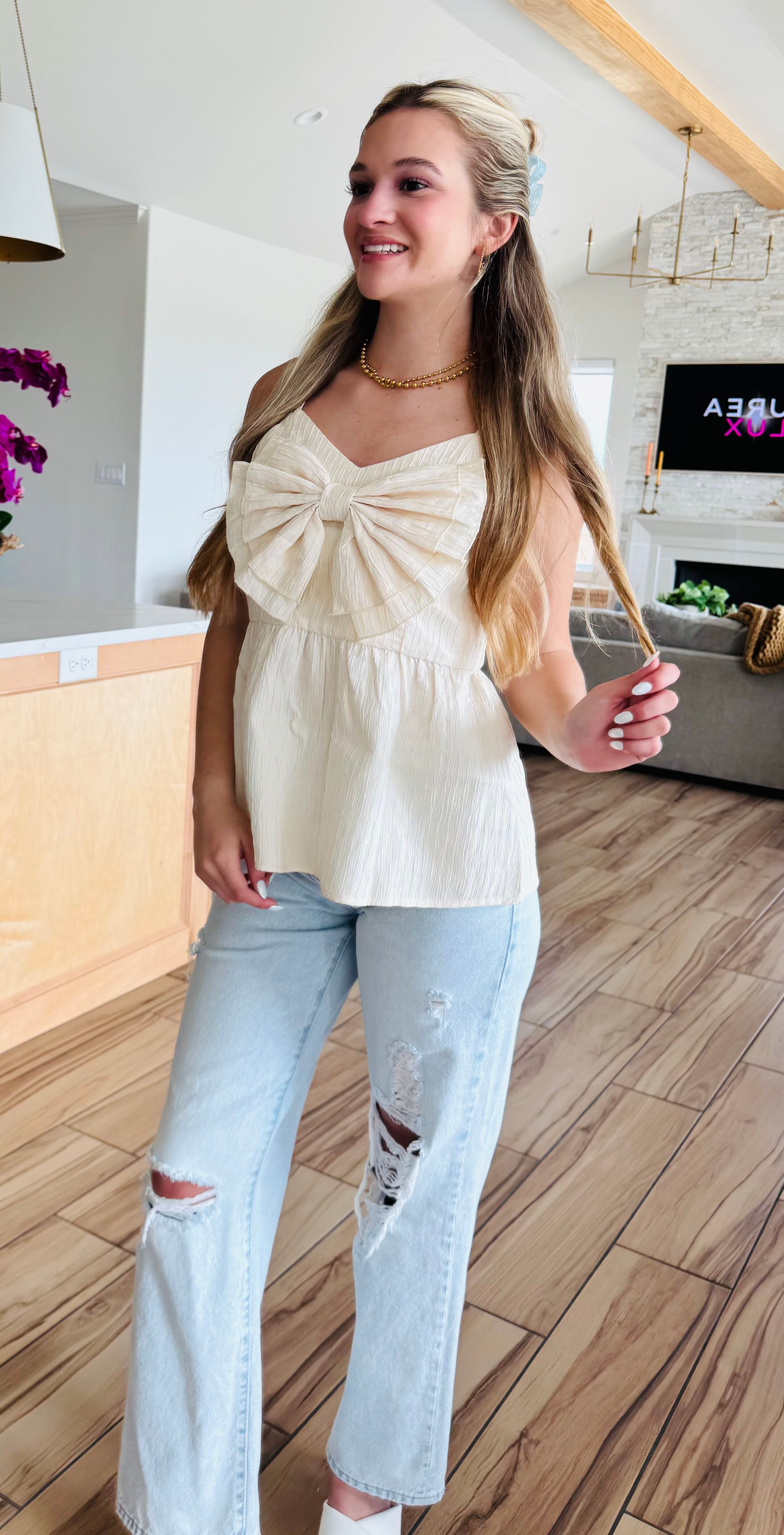 Model wearing the ECRU BABYDOLL TEXTURED BOW TOP, demonstrating its versatility when paired with jeans for a chic and effortless look.