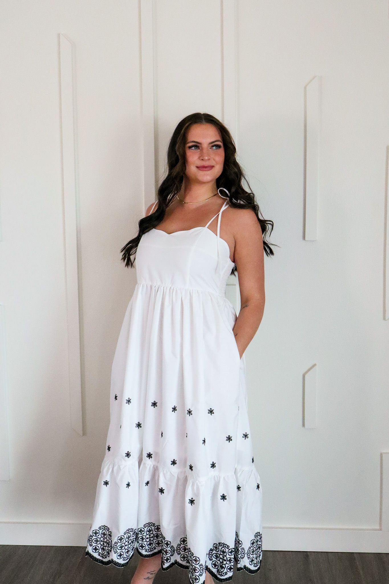 Stunning white and black embroidered maxi dress by Entro, featuring adjustable tie straps and intricate black embroidery details.