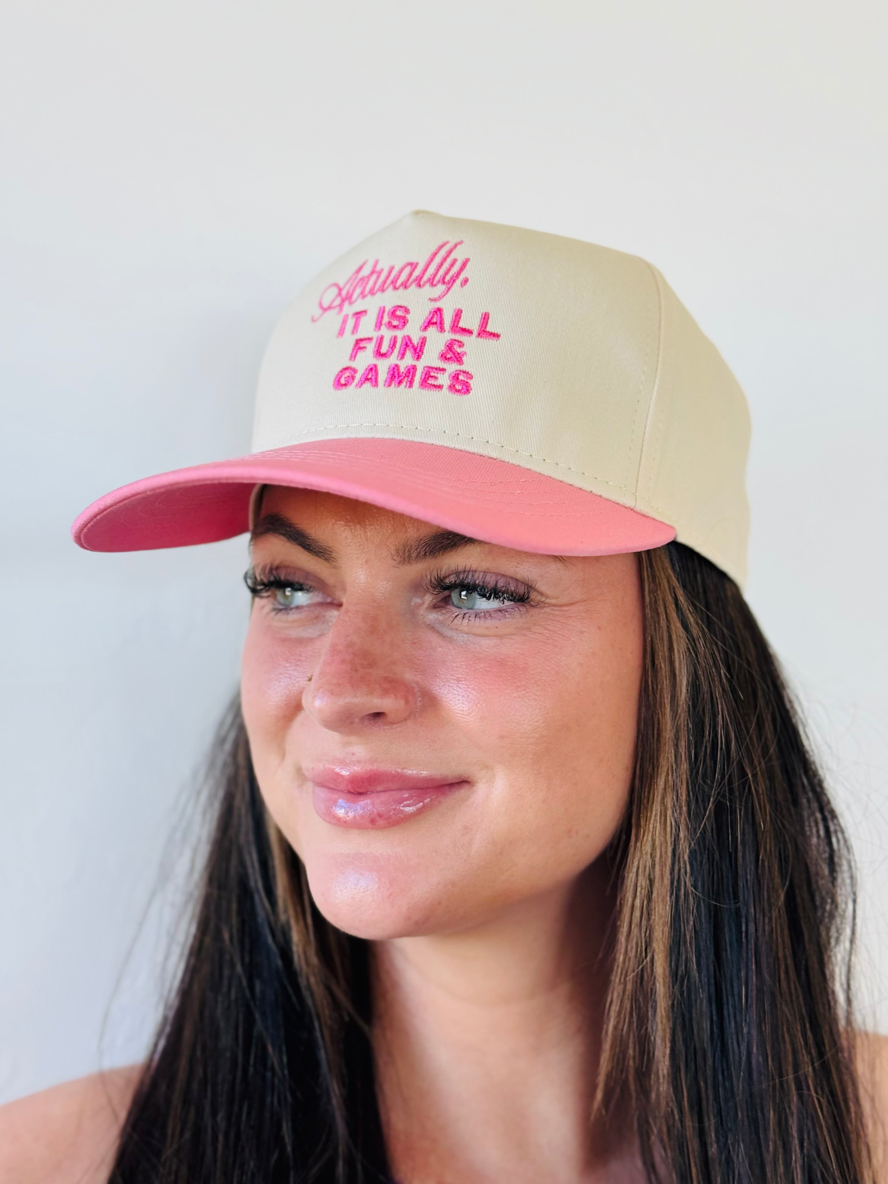 Lifestyle shot of the ACTUALLY IT IS ALL FUN & GAMES TRUCKER HAT worn outdoors, illustrating how it adds personality while protecting from the sun.