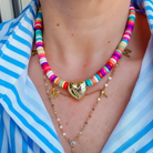 Stylish HEY GIRLIE BEADED NECKLACE featuring vibrant beads, a gold heart charm, and a 15" length with 2" extender, perfect for adding glamour to any outfit.