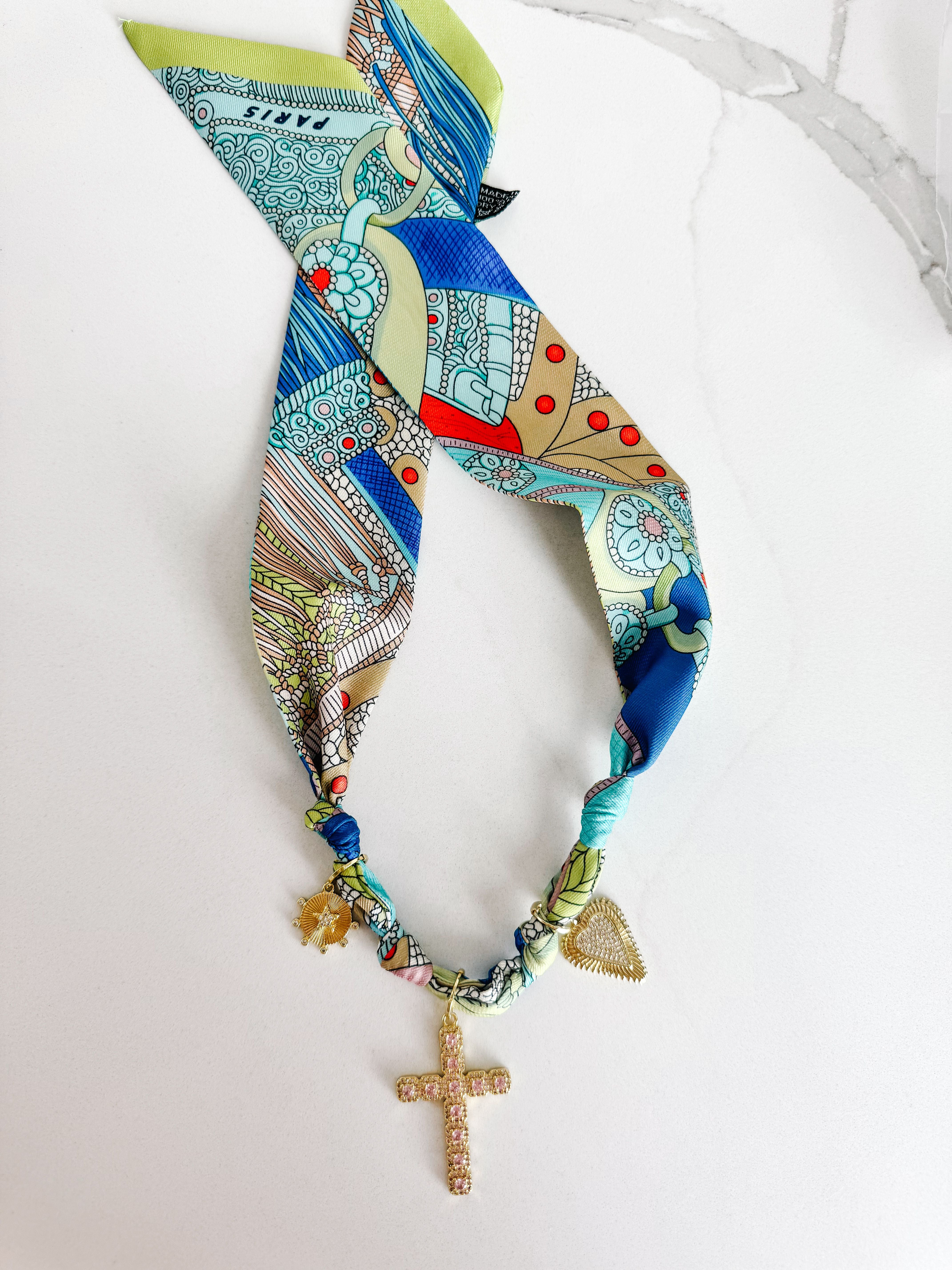 Close-up of PARIS SCARF NECKLACE featuring delicate details of the pink CZ cross, gold heart, and star pendants, ideal for enhancing any outfit.