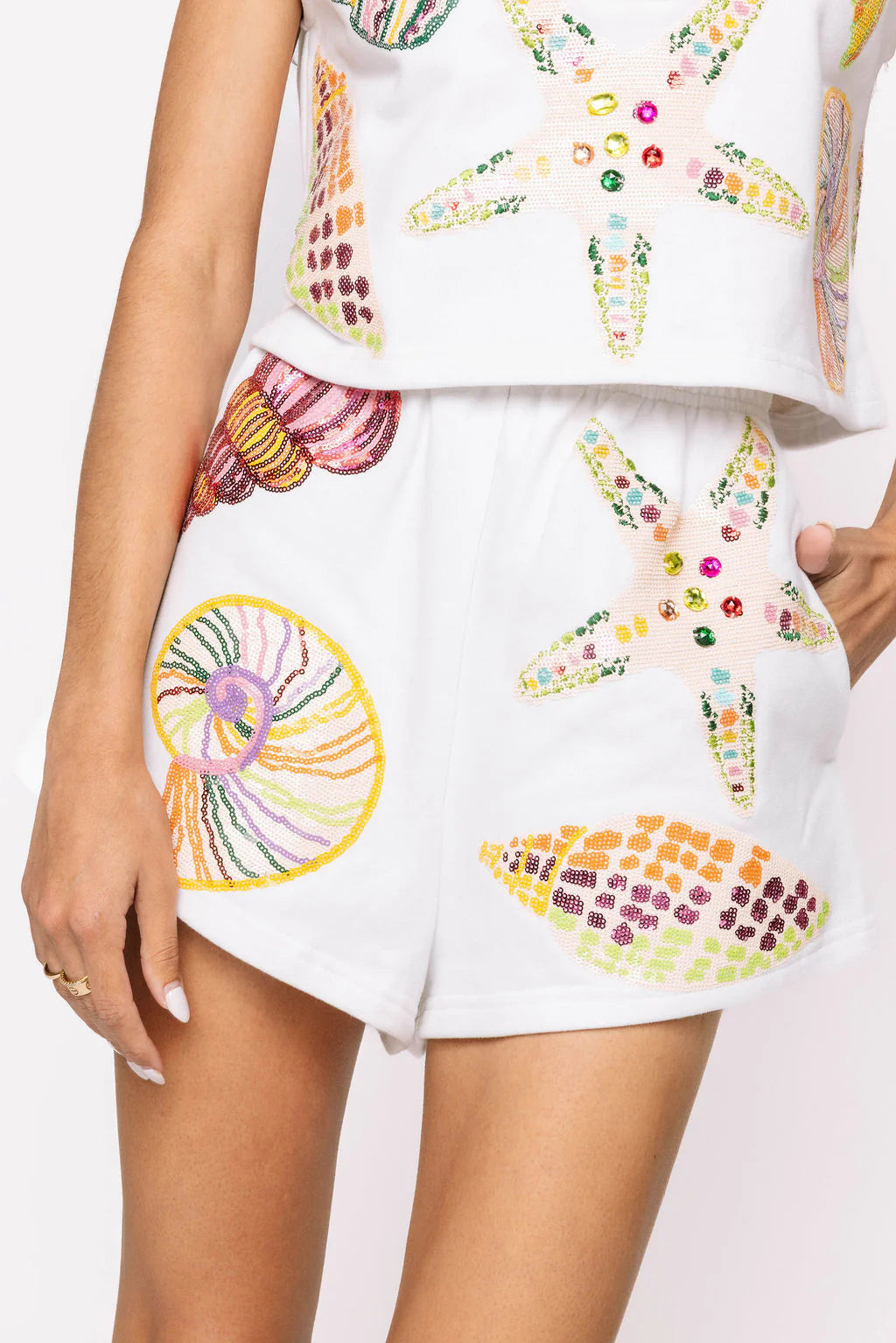 Queen of Sparkles White Multi Shell Short showcasing vibrant multicolored sequin shell designs, featuring a comfortable elastic waistband and side pockets, perfect for summer vacations and parties.